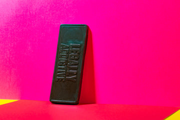 Black rectangular bar with embossed text 'LEGALLY ADDICTIVE' leaning against hot-pink background.